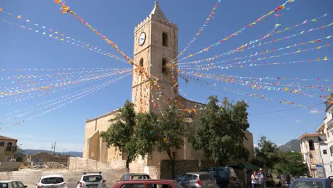 Toma-Panorámica-A-La-Izquierda-De-Una-Plaza-Cubierta-Con-Una-Bandera-De-Colores-En-Oliena-Cerdeña-Italia