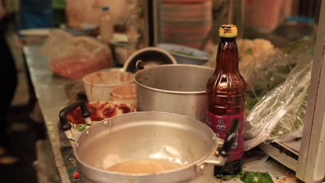 A-soft-upwards-shot-of-a-colourful-street-food-stall-in-Bangkok,-Thailand-serving-up-crispy-pork-noodles-in-a-small-restaurant