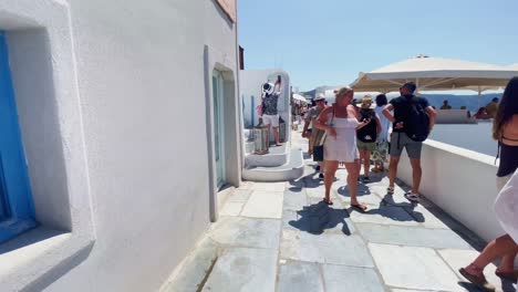 Oia-Santorini-Grecia-Isla-Viaje-Turístico-Paseo-Inmersivo,-Europa,-4k-|-Griego,-Egeo,-Mar,-Acantilado,-Océano,-Ciudad,-Vacaciones,-Compras,-Blanco,-Mármol,-Multitud,-Flores,-Viajero,-Gente,-Familia,-Mochila