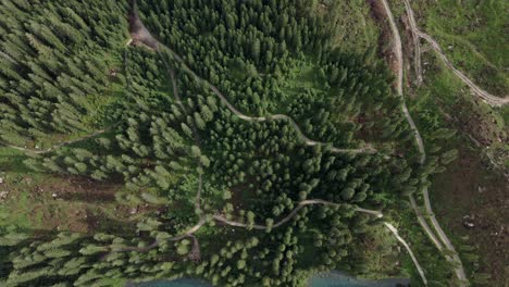 Reflexión-En-El-Lago-Carezza-Tomada-Con-Un-Dron-En-Los-Alpes-Italianos,-Dolomitas-Mientras-Hay-Montañas-Al-Fondo