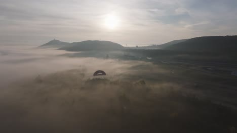 Vista-Aérea-De-La-Luz-Del-Sol-De-La-Mañana-Con-Pista-Poligonal-De-Carreras-Cubierta-De-Niebla