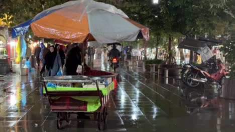 Comida-Callejera-Tienda-De-Comestibles-Fruta-Fresca-Vendiendo-En-Carretilla-Por-La-Noche-En-Un-Día-Lluvioso-Rasht-Gilan-Irán-Gente-Local-Mercado-De-Agricultores-En-El-Campo-Zona-Rural-Urbana-Amplia-Vista-Del-Paisaje-Urbano-Lluvia-Maravillosa