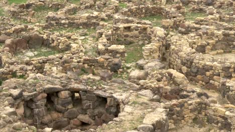 Lady-entering-the-Nuraghe-Barumini-in-Sardinia,-Italy-Tilting-shot-on-this-ancient-and-mysterious-building