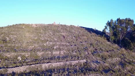 Aerial-drone-shot-flying-over-people-standing-on-the-top-of-Isla-del-sol,-mountain-island,-revealing-Lake-Titicaca,-in-Bolivia