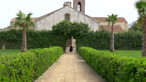 Mujer-Caminando-Por-Un-Sendero-Hacia-La-Puerta-De-Una-Iglesia