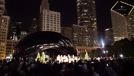 La-Gente-Escucha-Villancicos-Y-Celebra-Las-Vacaciones-De-Invierno-Cerca-De-Cloud-Gate-En-El-Centro-De-Chicago-Con-Rascacielos-Al-Fondo.