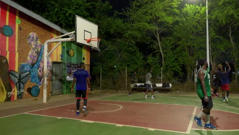 Atletas-De-Baloncesto-Negros-Juegan-Una-Exitosa-Acción-De-Ataque-En-Canchas-De-Baloncesto-Al-Aire-Libre-Jugando-Juntos-Por-La-Noche