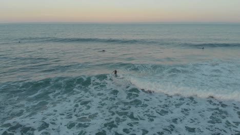 Surfer-Balanciert-Zur-Goldenen-Stunde-Auf-Den-Milden,-Schäumenden-Wellen-Des-Strandes-Santinho