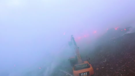 Excavadora-Luchando-Contra-Un-Incendio-Forestal,-Rodeada-De-Humo-Azul-Que-Se-Eleva,-En-Una-Noche-Oscura,-En-Amazonas,-Brasil,-Sudamérica---Toma-Aérea,-Drone