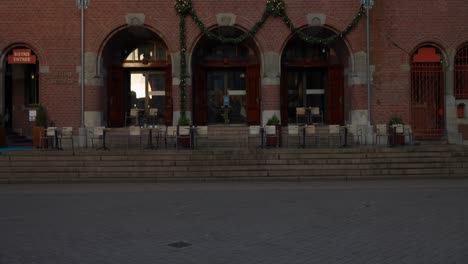 Tilt-up-establishing-shot-of-historic-brick-building-with-café-tables,-Amsterdam