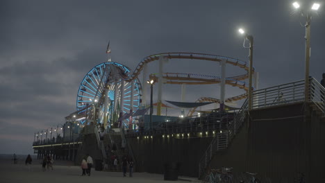 Landscape-View-of-Pacific-Park-on-Santa-Monica-Pier-during-Sunset-in-slow-motion-with-people-and-tourists-walking-in-the-background