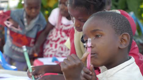 Young-african-boy-holds-up-crayola-drawing-color-pencil-and-paper