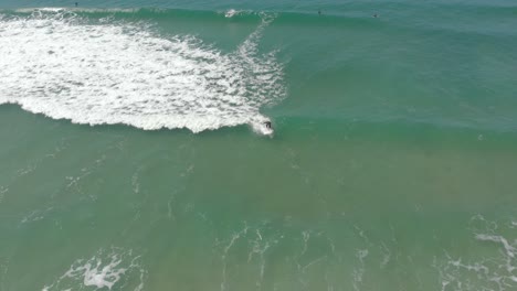 Surfista-Navegando-Y-Deteniéndose-En-Las-Suaves-Olas-Espumosas-De-Santinho-En-La-Ciudad-De-Florianópolis,-Brasil