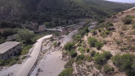 Toma-Aérea-De-Drones,-Vuela-A-Lo-Largo-De-Una-Carretera-Vacía-Hacia-Una-Industria-Abandonada