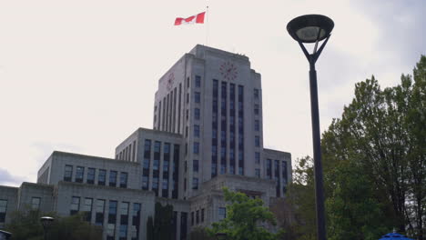 AN-UPWARD-TILT-FULL-SHOT-of-Vancouver-City-Hall-as-a-Group-of-Protestors-Walk-by