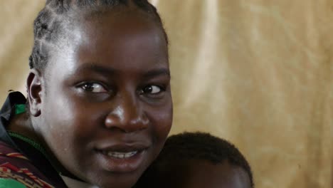 African-child-and-mother-holds-baby,-traditional-hair-style-on-plain-background