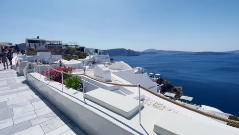 Oia-Santorini-Greece-Island-Travel-Tourist-Immersive-Walk,-Europe,-4K-|-Greek,-Aegean,-Sea,-Cliffside,-Ocean,-City,-Vacation,-Shopping,-White,-Marble,-Crowd,-Flowers,-Traveler,-People,-Rail,-Scenic