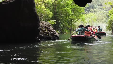 Row-boats-Ninh-Binh-Vietnam,-tourists-leaving-rowing-out-of-cave-in-slo-motion