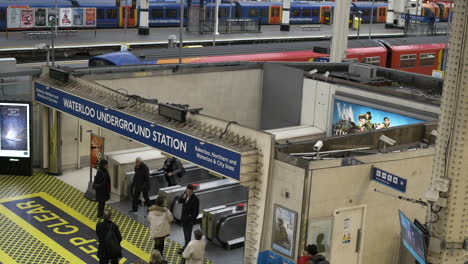 Still-shot-of-train-station-platform-entry-gate-with-people-walking-and-boarding-Waterloo-Station-London-UK