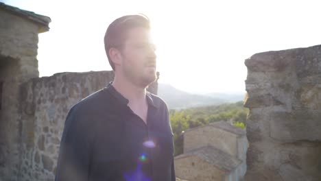 Slowmotion-shot-of-a-man-walking-through-castle-ruins-during-sunset