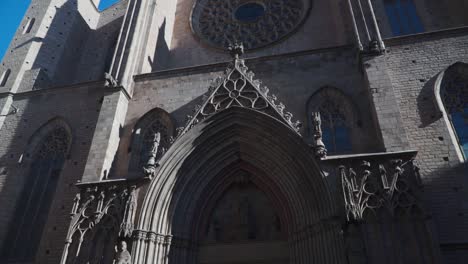 Tiro-Inclinado-Hacia-Arriba-Y-Hacia-Abajo,-Vista-Panorámica-Del-Diseño-Exterior-De-Una-Iglesia-En-Barcelona-España,-Pájaro-Volando-En-El-Cielo-Azul