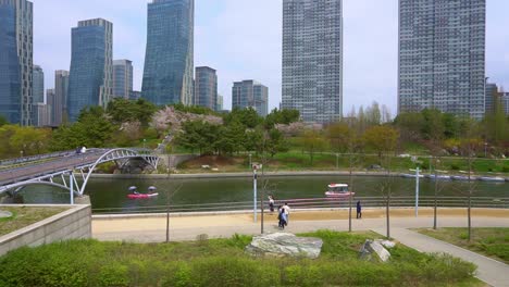 Gente-Caminando-En-Un-Parque-Cercano-A-Edificios-De-Gran-Altura