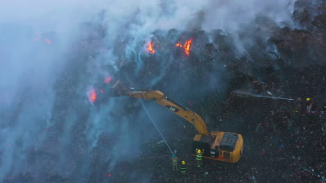 Excavadora-Y-Bomberos-Tratando-De-Extinguir-Un-Incendio-Forestal,-Humo-Azul-Elevándose,-En-Una-Noche-Oscura,-En-Amazonas,-Brasil,-Sudamérica---Aéreo,-Descendente,-Disparo-De-Drone