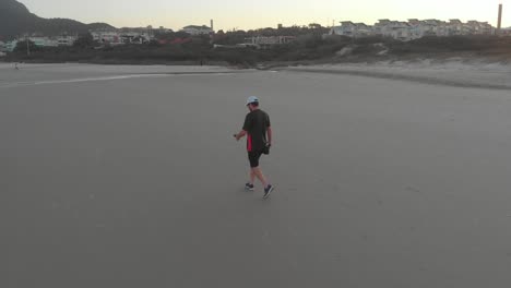 Free-tourist-wandering-and-cherishing-freedom-on-the-sandy-beach-of-Santinho-at-golden-hour