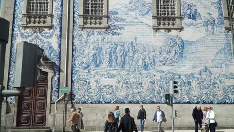 Tiro-Inclinado,-Gente-Caminando-Por-La-Plaza-Del-Pueblo,-Vista-Panorámica-Del-Diseño-Exterior-De-La-Iglesia-De-Nuestra-Señora-Carmon-En-Porto,-Portugal