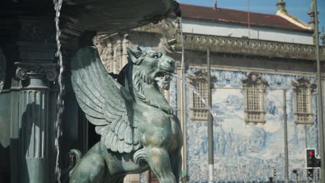 Mittlere-Bewegte-Aufnahme,-Malerische-Ansicht-Alter-Geflügelter-Löwenbrunnen-Auf-Dem-Stadtplatz-In-Porto,-Portugal,-Kirche-Igreja-Do-Carmo-Im-Hintergrund