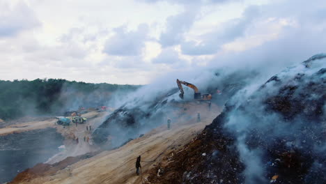 Drone-shot-over-firemen-and-firetrucks,-quelling-a-fire-at-a-junkyard,-in-Dominican-Republic---rising,-aerial-view