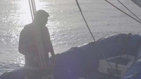 A-man-is-standing-on-a-blue-boat-that-is-hanging-on-some-ropes-of-a-cruise-on-the-ocean-of-the-Galapagos-islands