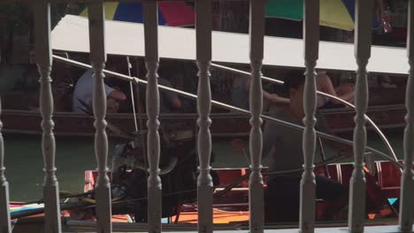 Panning-Right-Shot,-Pump-boat-passing-by-on-the-floating-market-in-Thailand,-tourists-on-a-boat-in-the-background