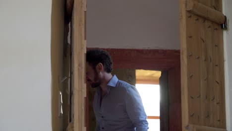 Slow-motion-shot-though-a-wooden-door-of-a-man-walking-on-a-hallway