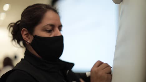 Woman-employee-with-mask-writing-on-magnetic-board-in-slow-motion