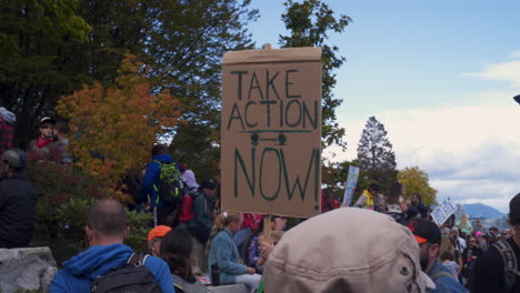 Eine-Demonstrantin-Hält-Ein-Schild-Mit-Der-Aufschrift-„Machen-Sie-Jetzt-Maßnahmen.“