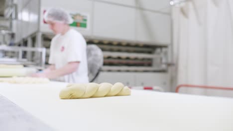 Tiefansicht-Von-Frischem-Dreifach-Teig-Baguette-Auf-Einem-Laufenden-Förderband-Mit-Arbeiter-Im-Hintergrund