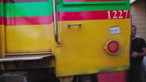 POV-Slow-motion-Shot,-Train-passing-by-the-railroad-on-the-Maeklong-Market-in-Thailand,-Vendors-preparing-their-stands-in-the-background