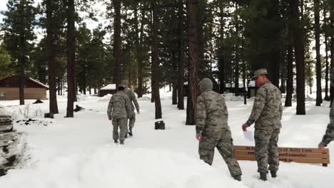 Military-men-in-uniform-walking-in-the-snow-and-exploring-the-woods,-hand-held-shot