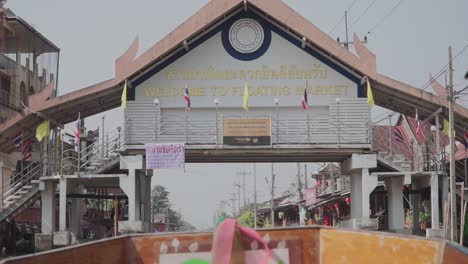 Upshot,-moving-forward-in-a-wooden-boat,-Scenic-view-of-Bridge-Signage-in-Thailand-Floating-Market