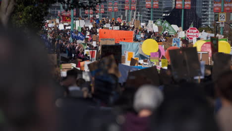 Enfoque-De-Un-Mar-De-Personas-Marchando-Y-Agitando-Carteles-En-Una-Manifestación-Sobre-El-Cambio-Climático.