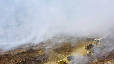 Luftaufnahme-Einer-Schwenkdrone-Mit-Blick-Auf-Müllwagen-Und-Schrottfahrzeuge,-Inmitten-Eines-Schrottplatzfeuers,-Aufsteigender-Rauch,-Sonniger-Tag,-In-Vertedero-De-Duquesa,-Santo-Domingo,-Dominikanische-Republik