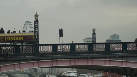 El-Autobús-Turístico-De-Londres-Cruza-El-Puente-De-Lambeth-En-Un-Día-Nublado-Con-El-London-Eye-Al-Fondo