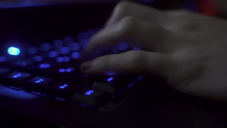 Die-Stabile-4K-Aufnahme-Zeigt-Eine-Nicht-Wiederzuerkennende-Person,-Die-Auf-Einer-Blau-Beleuchteten-Tastatur-Mit-Den-Tasten-Der-Tastatur-Spielt-Und-Schreibt