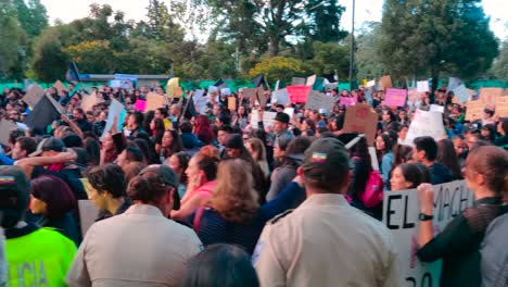 A-crowd-of-men-and-women-are-holding-signs-and-flags-are-protesting-as-several-police-officers-supervise