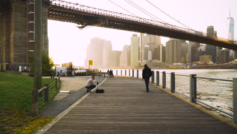 Riverwalk-Cerca-Del-Puente-De-Brooklyn-En-Nueva-York-Al-Atardecer---POV-Plano-Amplio