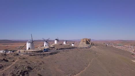 Disparo-De-Dron,-Camión-A-La-Derecha-En-Movimiento-Lento-Frente-A-Un-Antiguo-Molino-De-Viento-En-Consuegra