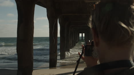 Female-photographer-takes-pictures-underneath-the-pier-at-Manhattan-Beach