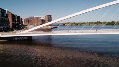 Aerial-view-of-people-walking-on-the-Isoisansilta-bridge,-on-a-sunny-day,-in-Kalasatama,-Helsinkii,-Uusimaa,-Finland---Dolly,-drone-shot