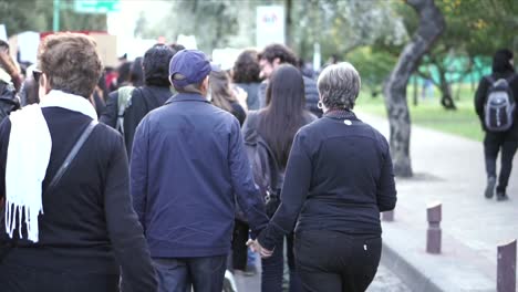 A-couple-of-old-people-are-walking-together-as-they-hold-signs-during-a-protest-and-march-on-the-International-Women's-Day